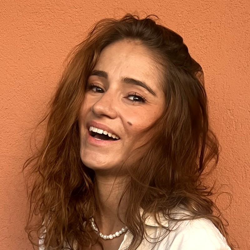Carla Cacciatore, fondatrice de Flair., souriante devant un mur ocre